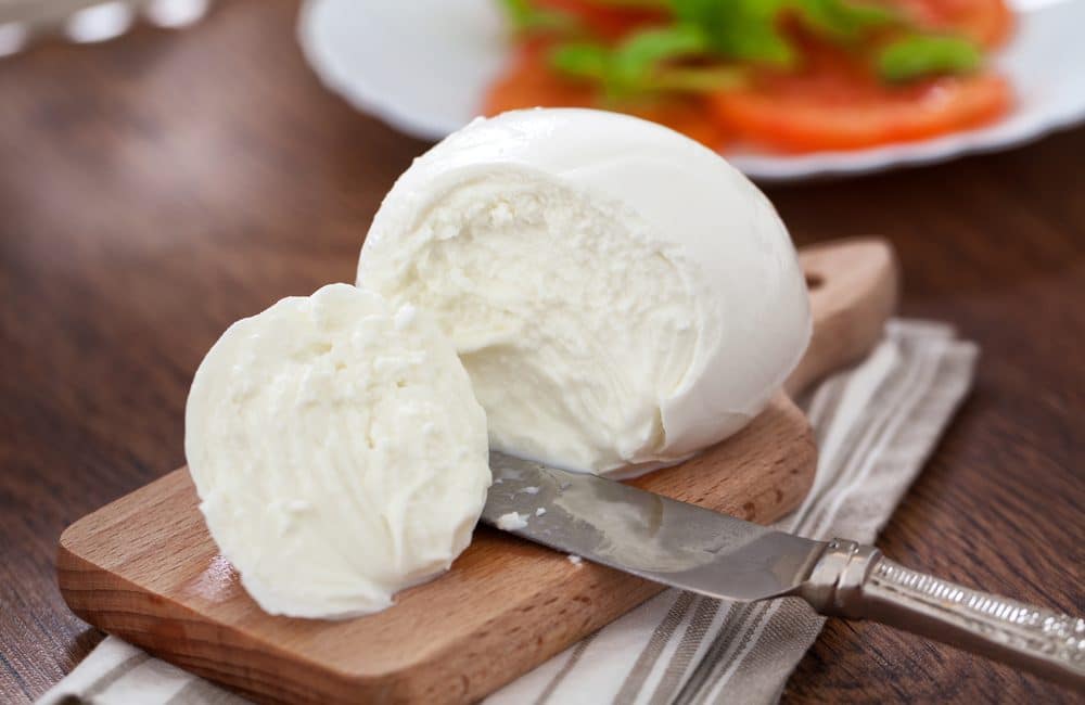 Boules de Mozzarella posées sur une planche en bois. Ce fromage est sans risque pour les femmes enceintes.