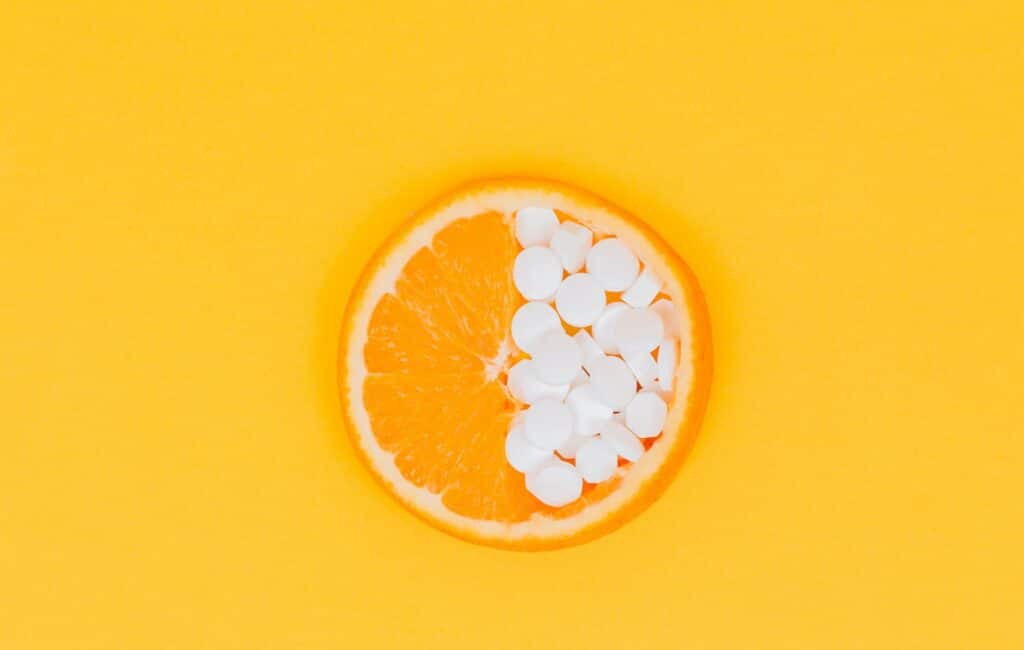 Tranche d'orange coupée avec des pilules de vitamine c sur la moitié de la tranche