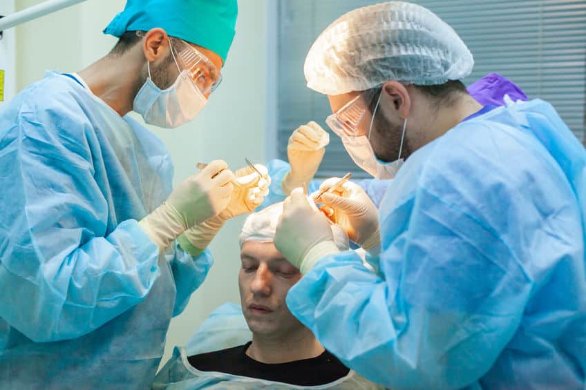 Deux chirurgiens réalisants une greffe de cheveux sur un patient atteint de calvitie